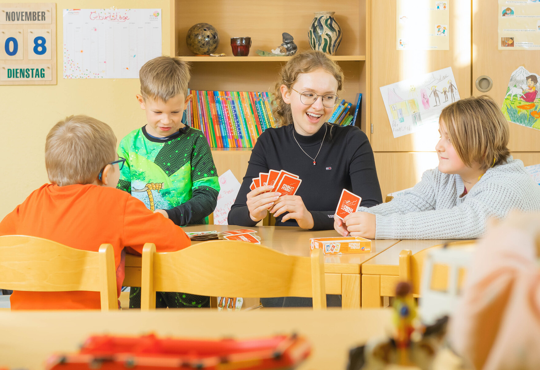 FSJlerin spielt mit Kindern ein Kartenspiel